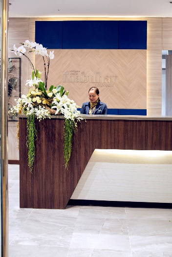 A person standing at a reception desk Description automatically generated